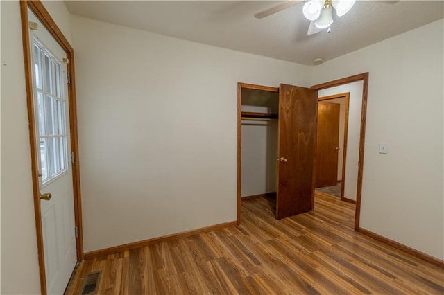 unfurnished bedroom featuring wood finished floors, visible vents, a closet, and baseboards