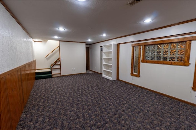 finished basement with ornamental molding, built in features, stairway, carpet, and wainscoting