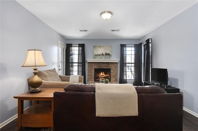 living room featuring a wealth of natural light, visible vents, a fireplace, and dark wood-style flooring