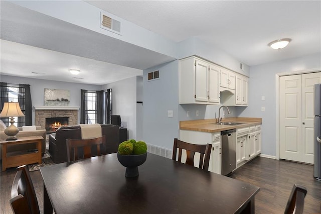 dining room featuring visible vents, baseboards, a stone fireplace, and dark wood-style flooring