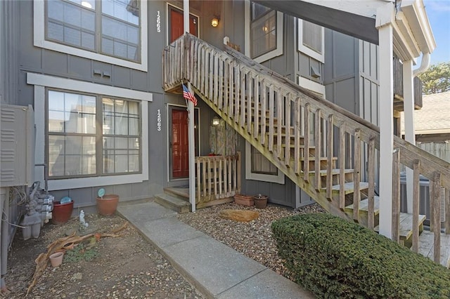 view of exterior entry featuring central AC unit and board and batten siding