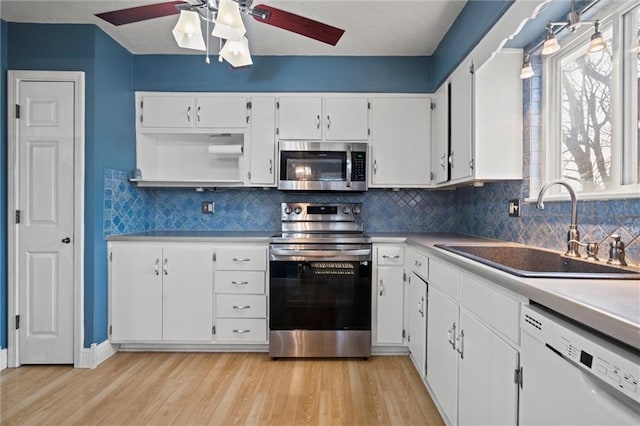 kitchen with light wood-style flooring, a sink, white cabinetry, stainless steel appliances, and ceiling fan