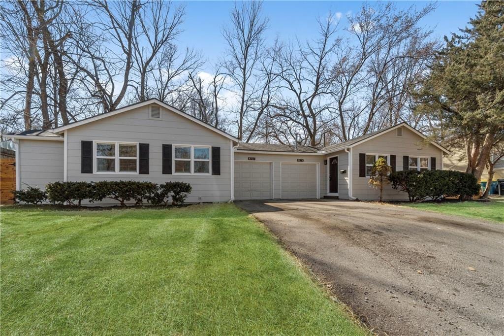 ranch-style house featuring a front lawn, an attached garage, and driveway