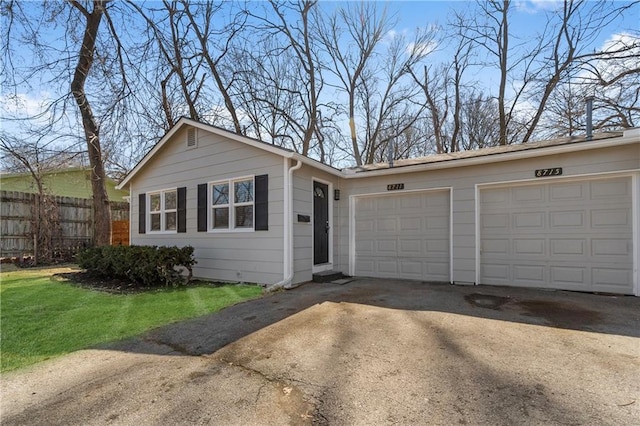 single story home featuring a front lawn, an attached garage, fence, and driveway