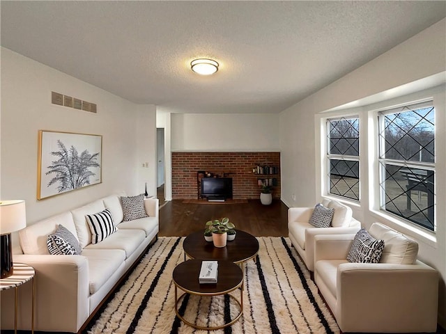 living area featuring visible vents, a textured ceiling, and wood finished floors