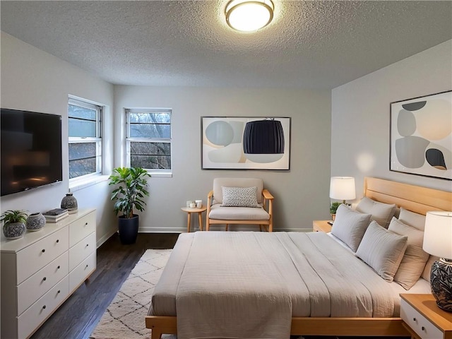 bedroom with baseboards, a textured ceiling, and dark wood-style floors