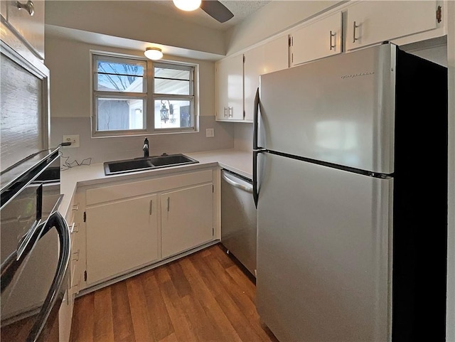 kitchen featuring wood finished floors, a sink, light countertops, white cabinets, and appliances with stainless steel finishes
