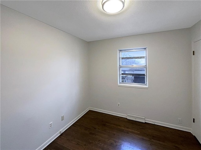 unfurnished room featuring visible vents, wood finished floors, and baseboards
