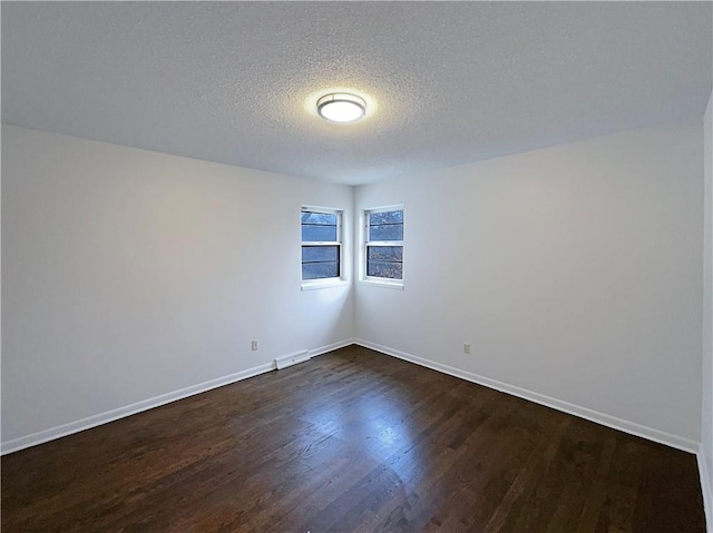 unfurnished room featuring baseboards, a textured ceiling, and dark wood-style floors