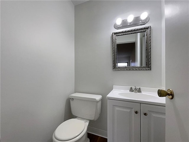 bathroom with toilet, vanity, and baseboards