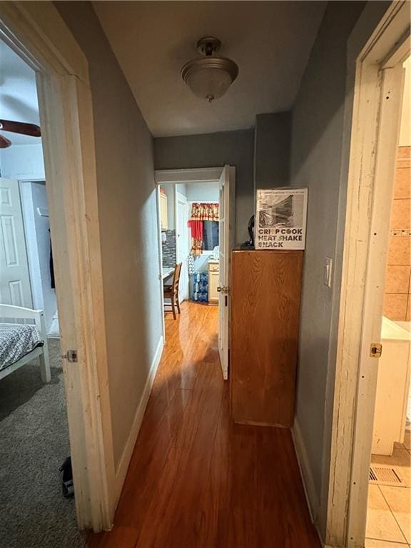 corridor with baseboards and wood finished floors