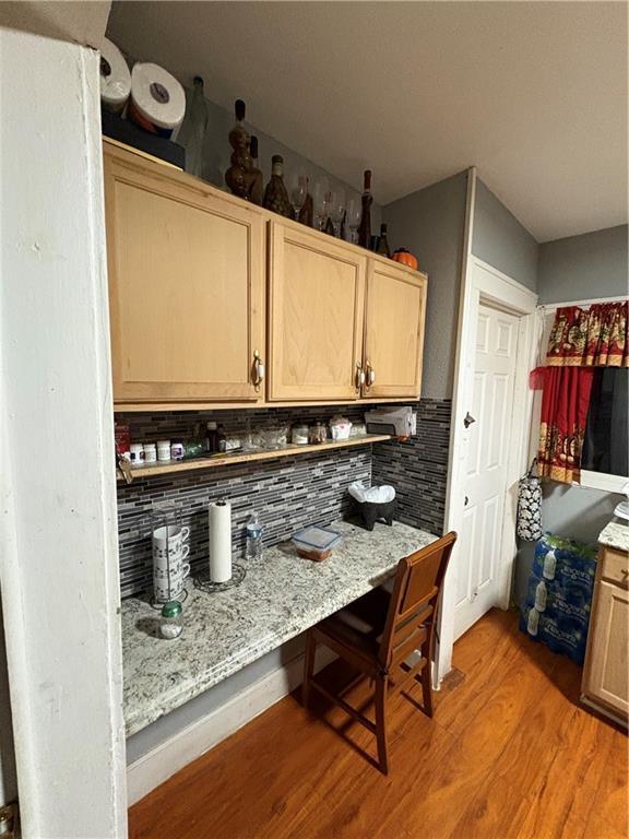 kitchen featuring light wood-style flooring, light stone countertops, backsplash, and light brown cabinetry