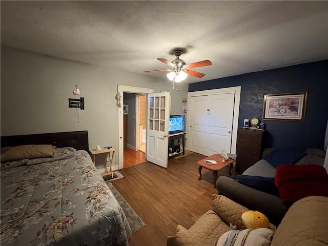 bedroom featuring a textured ceiling, ceiling fan, and wood finished floors