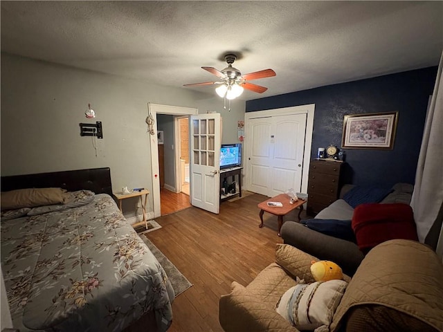 bedroom featuring a ceiling fan, wood finished floors, and a textured ceiling