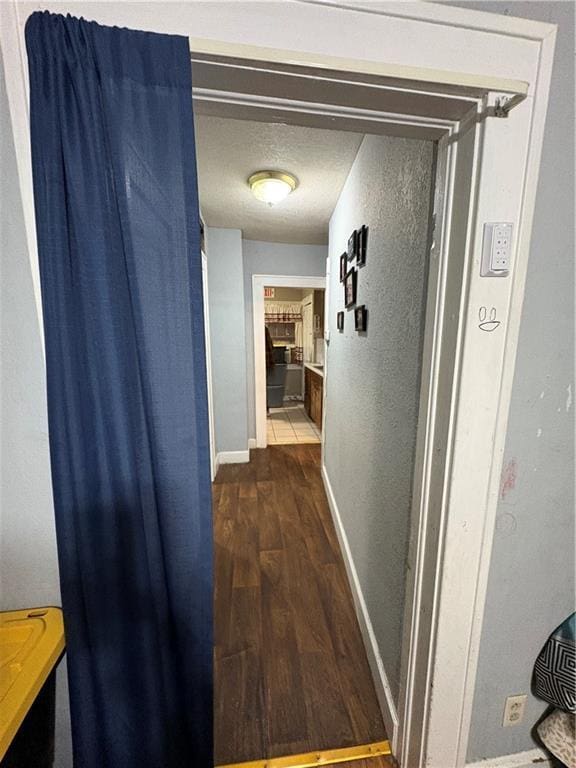 hall featuring baseboards and dark wood-style flooring