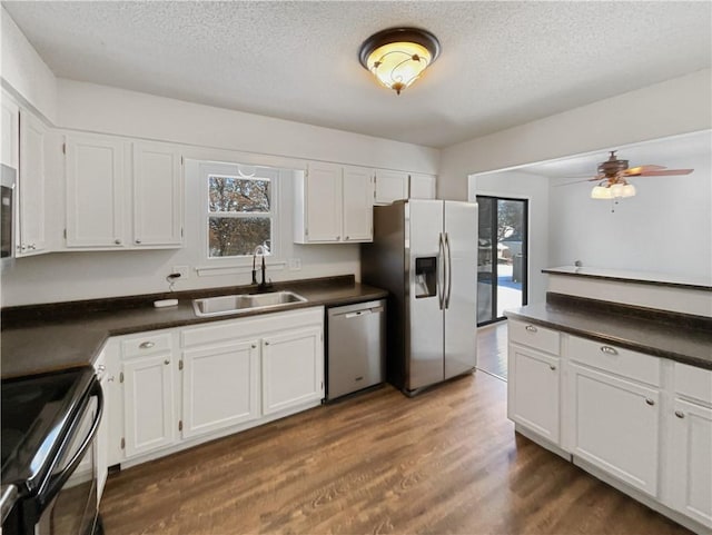 kitchen with a sink, dark countertops, appliances with stainless steel finishes, and dark wood-style floors