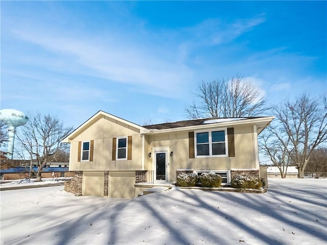 view of front of house featuring an attached garage, stone siding, and stucco siding