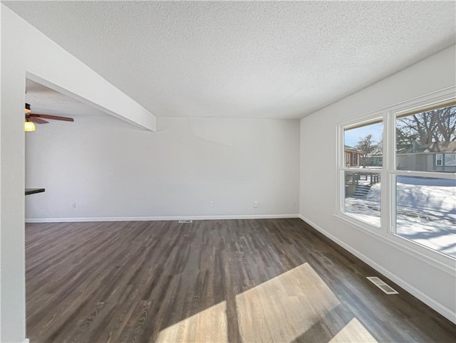 spare room with dark wood-style floors, visible vents, a textured ceiling, and baseboards