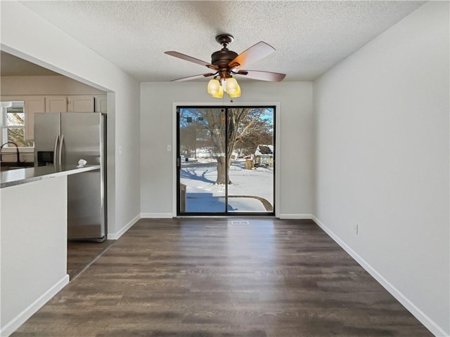 unfurnished dining area featuring a sink, baseboards, dark wood-type flooring, and ceiling fan