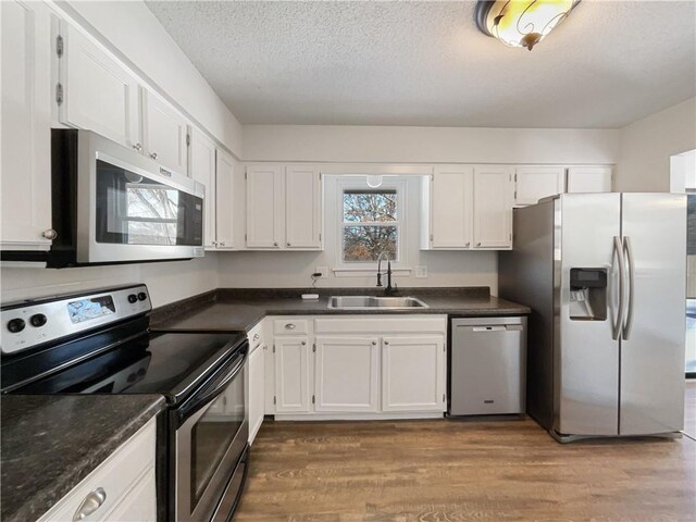 kitchen with a sink, dark countertops, appliances with stainless steel finishes, and dark wood finished floors