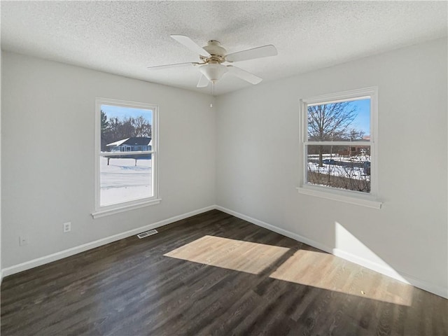 spare room featuring visible vents, baseboards, dark wood-type flooring, and a textured ceiling