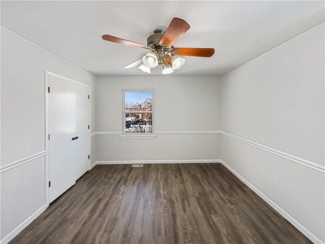 spare room with baseboards, dark wood-type flooring, and a ceiling fan