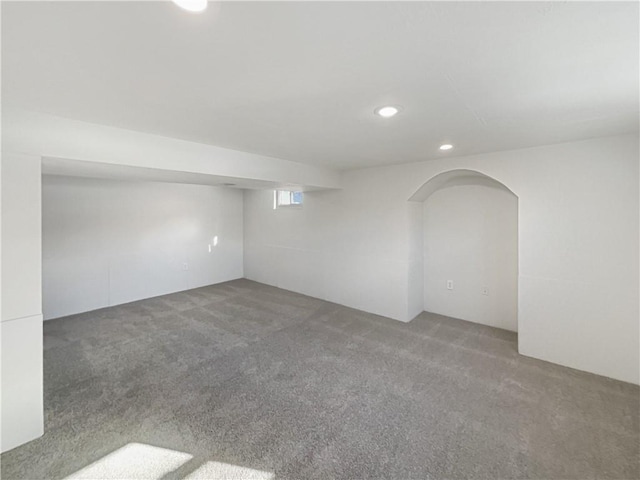 basement featuring carpet flooring, recessed lighting, and arched walkways