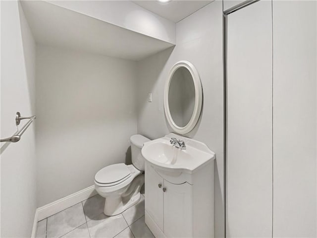 half bath with tile patterned flooring, toilet, vanity, and baseboards