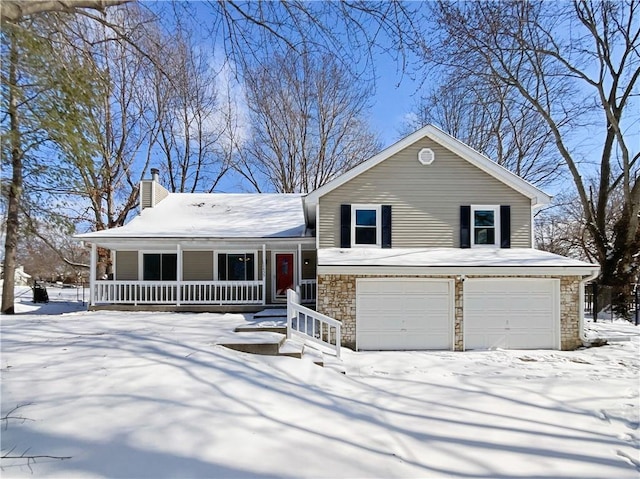 split level home with stone siding, a porch, a chimney, and a garage