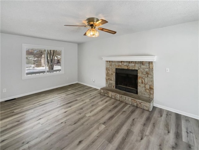 unfurnished living room featuring a ceiling fan, wood finished floors, baseboards, and a textured ceiling