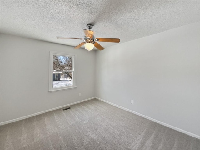 unfurnished room featuring visible vents, a textured ceiling, carpet flooring, baseboards, and ceiling fan