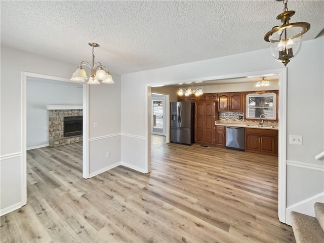 kitchen with a sink, an inviting chandelier, light countertops, and stainless steel appliances