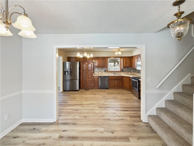 kitchen featuring a sink, backsplash, stainless steel appliances, light wood-style floors, and light countertops