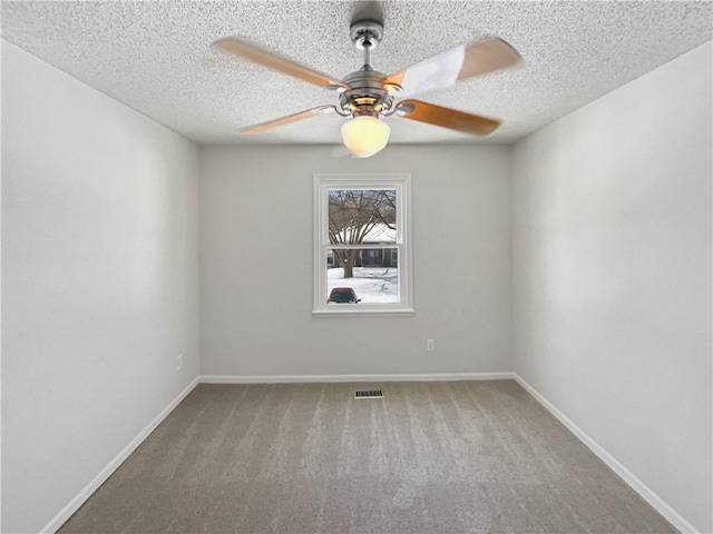 carpeted empty room featuring visible vents, ceiling fan, a textured ceiling, and baseboards