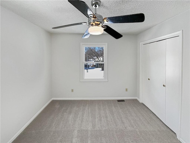 unfurnished bedroom featuring visible vents, carpet floors, a textured ceiling, and a closet