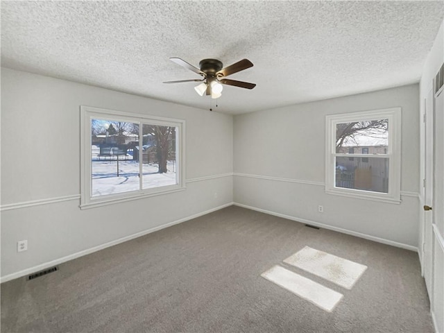 unfurnished room with visible vents, ceiling fan, baseboards, and carpet