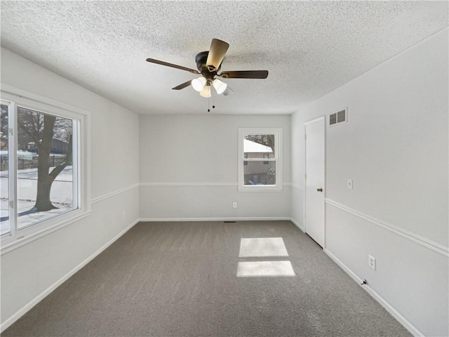 carpeted spare room with a ceiling fan, baseboards, visible vents, and a textured ceiling