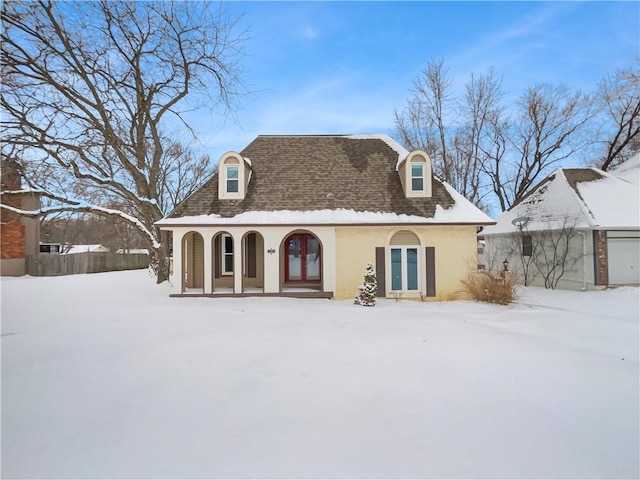 view of front facade with stucco siding, covered porch, and a shingled roof