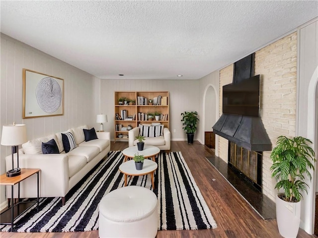 living area with built in shelves, a textured ceiling, and wood finished floors