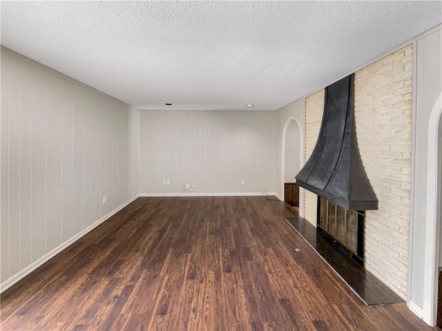 unfurnished living room featuring dark wood-style floors, a textured ceiling, and baseboards