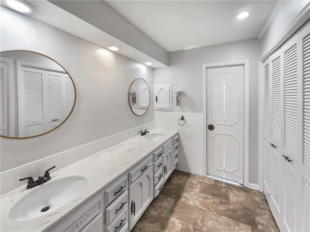 bathroom featuring double vanity, tile walls, a closet, and a sink