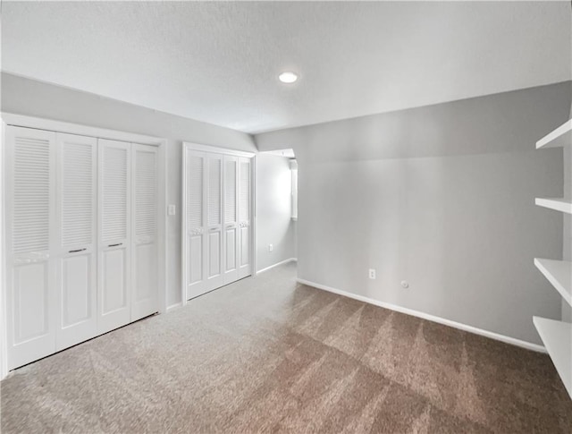 unfurnished bedroom featuring carpet flooring, baseboards, and multiple closets