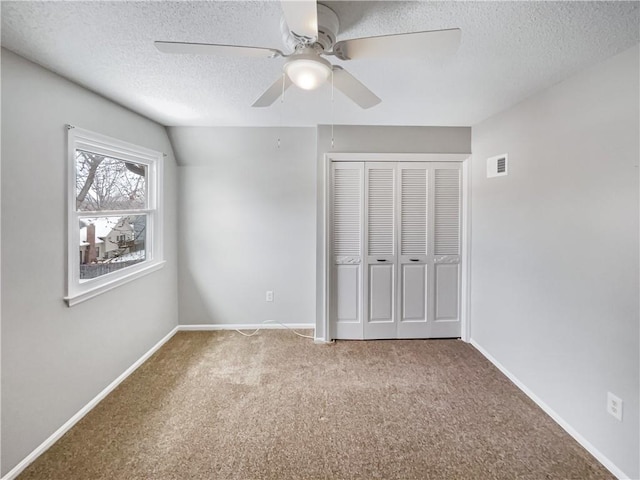 unfurnished bedroom featuring visible vents, baseboards, a closet, a textured ceiling, and carpet flooring