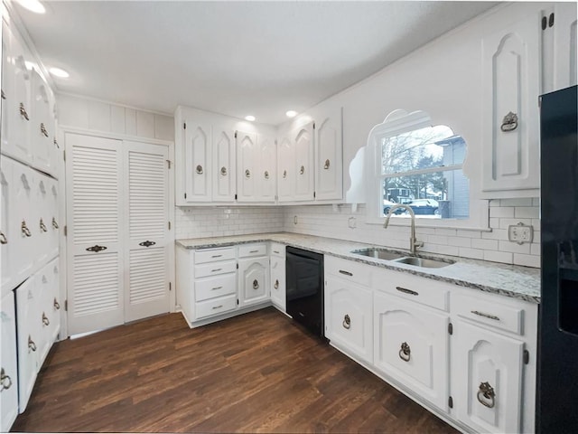 kitchen with dark wood-type flooring, black appliances, a sink, white cabinetry, and light stone countertops