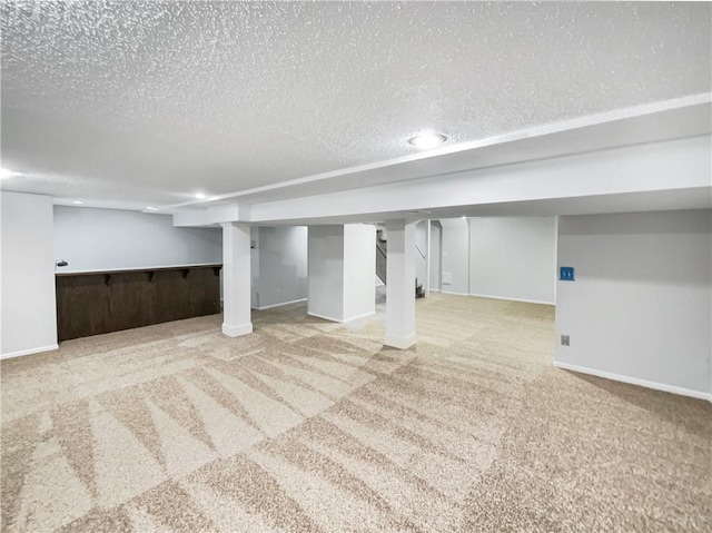 finished basement with baseboards, a textured ceiling, and carpet flooring