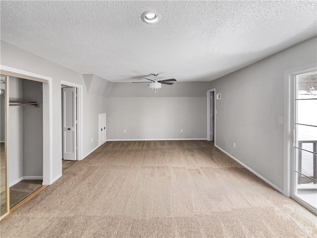 unfurnished bedroom featuring two closets, a ceiling fan, a textured ceiling, baseboards, and light colored carpet