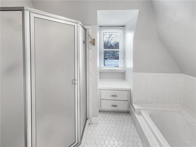 bathroom with a shower stall, a bath, vaulted ceiling, and a textured ceiling