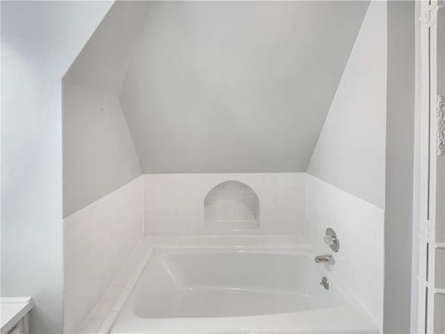 full bath featuring vaulted ceiling and a bath