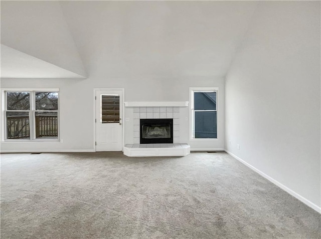 unfurnished living room with baseboards, lofted ceiling, carpet, and a tile fireplace