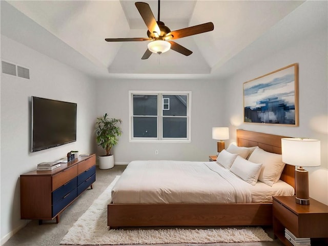 bedroom with visible vents, baseboards, ceiling fan, light carpet, and a raised ceiling